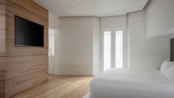 A modern bedroom with a wooden wardrobe, a flat-screen TV, a large bed, and a sliding door leading to a balcony.
