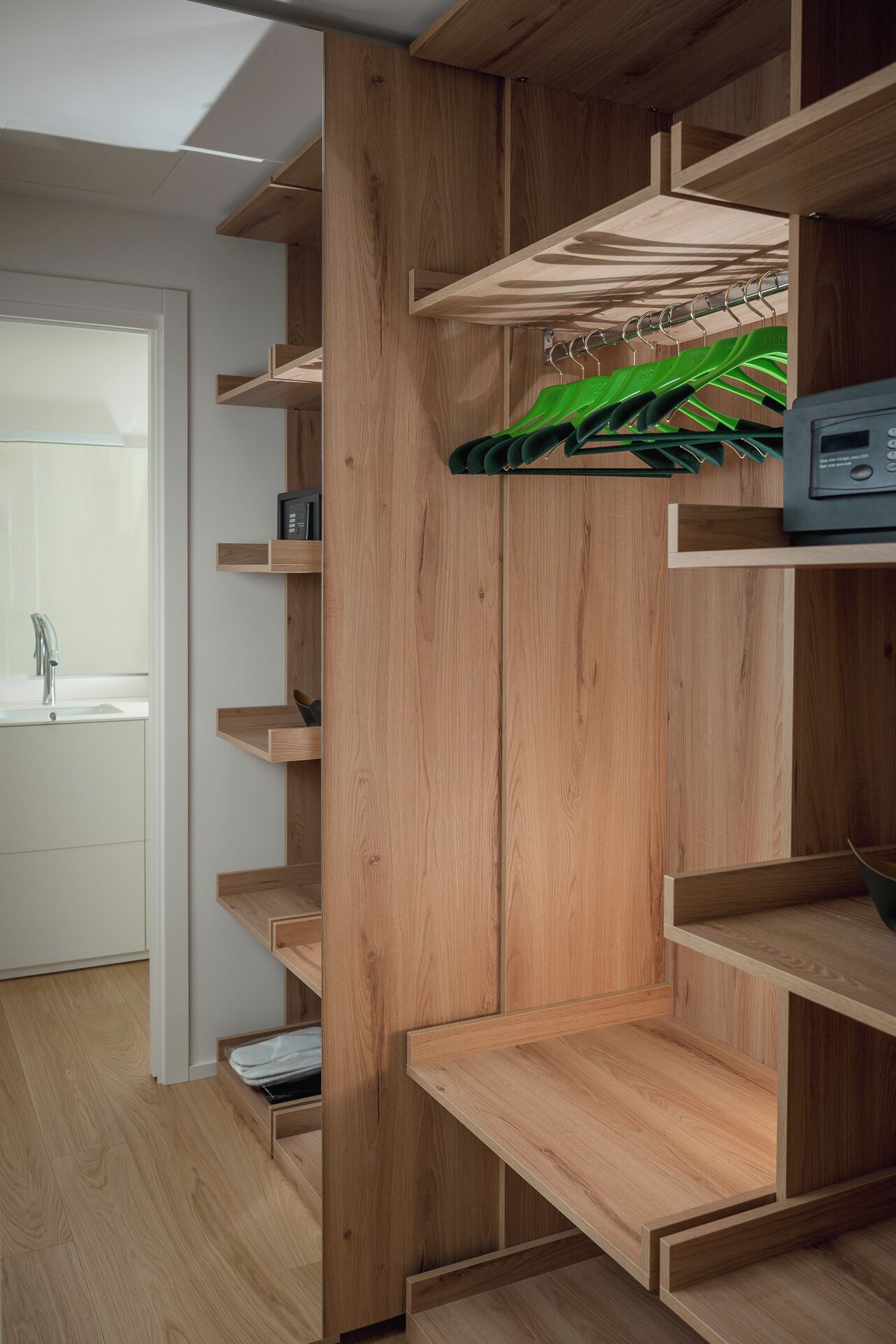 A modern, multi-tiered wooden shelving unit in a room with a minimalist design.
