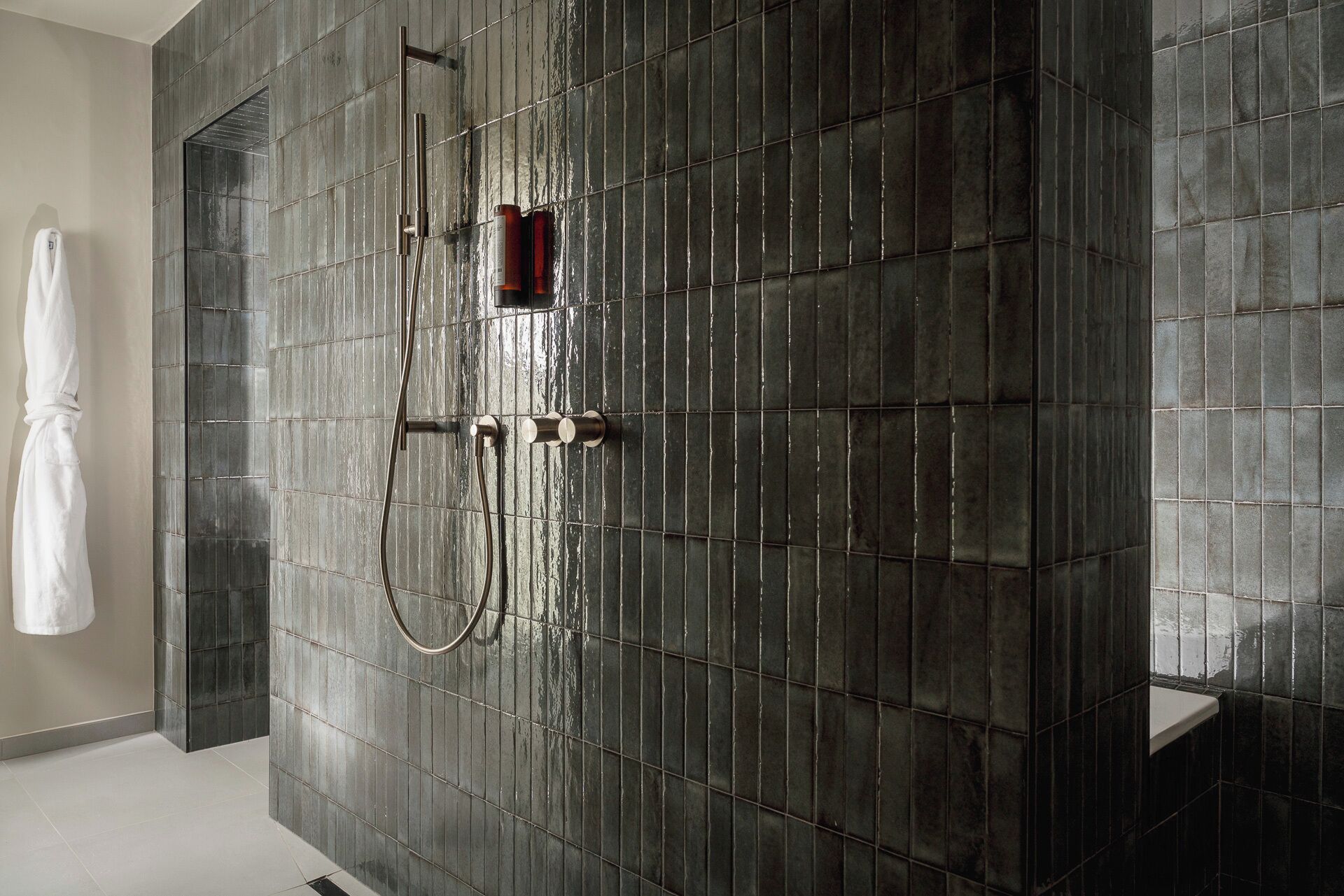 Une salle de bain moderne dotée d’une grande douche, d’un porte-serviettes et d’un lavabo.