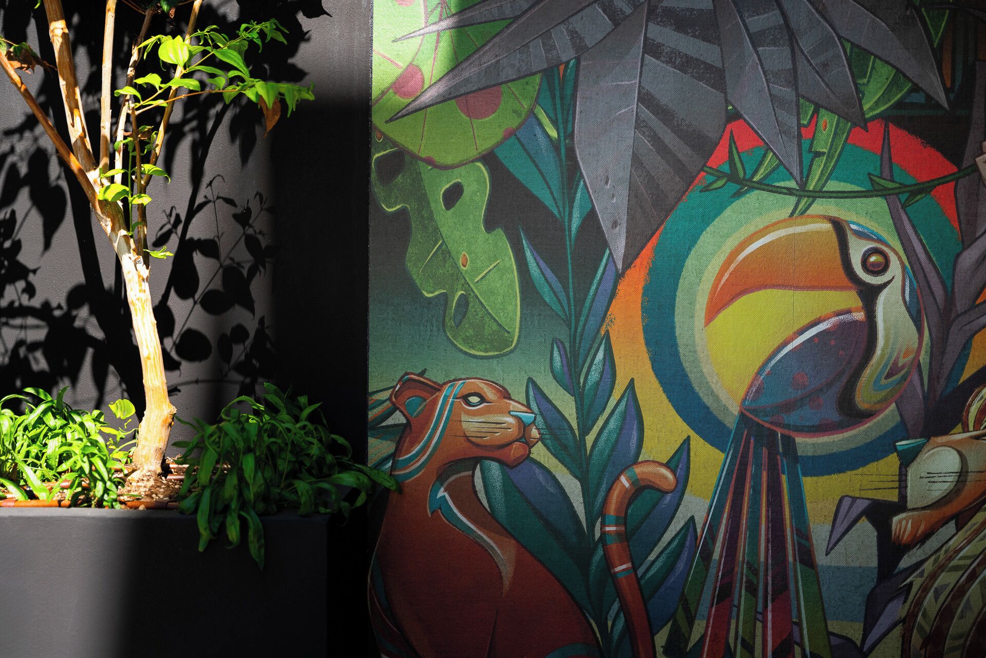 Un mural con un colorido guacamayo y un perro.