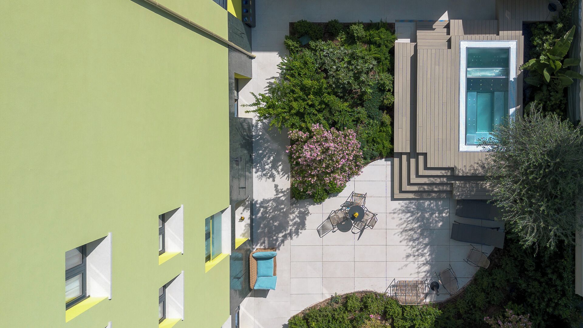 Una terraza en la azotea con piscina, zona de estar y abundante vegetación.