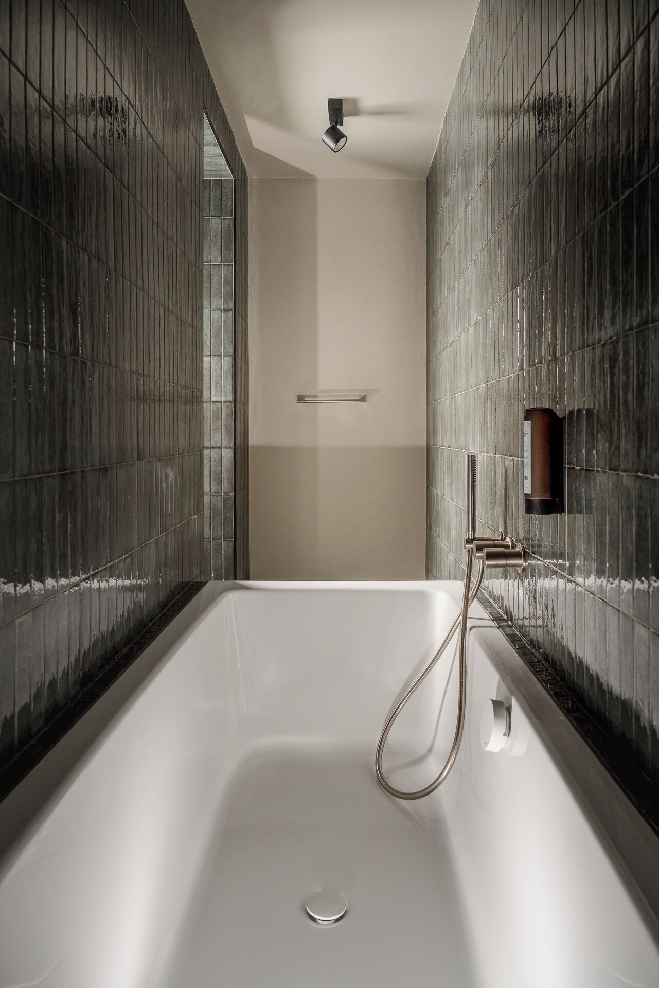 Une salle de bain moderne dotée d’une grande baignoire, d’une douchette et d’un porte-serviettes fixé au mur.