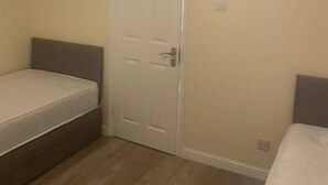 Una habitación pequeña con una cama individual, una puerta y un interruptor de luz en la pared.