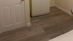 Una habitación con piso de madera, una puerta blanca y un armario blanco.