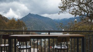 A balcony with a table and two chairs, overlooking a mountainous landscape with autumn foliage. - Zuiyu Shanfang Hotel (Ngawa Autonomous Prefecture)