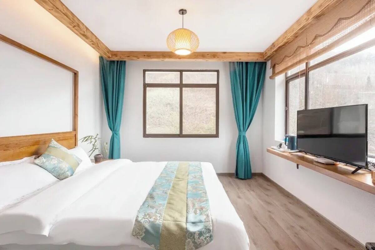 Un dormitorio con cama, cortinas, televisor y ventana.