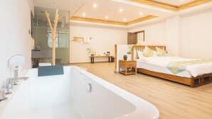 A modern bedroom with a large bathtub, wooden flooring, a bed with a wooden headboard, and a bedside table with a lamp. - Zuiyu Shanfang Hotel (Ngawa Autonomous Prefecture)