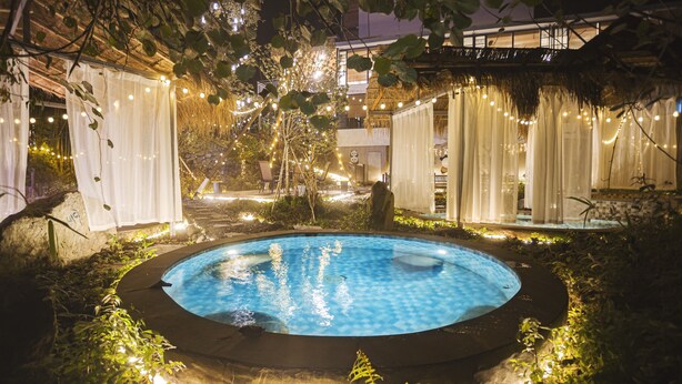 A circular pool surrounded by greenery and string lights, with a building in the background. - Zuiyu Shanfang Hotel (Ngawa Autonomous Prefecture)