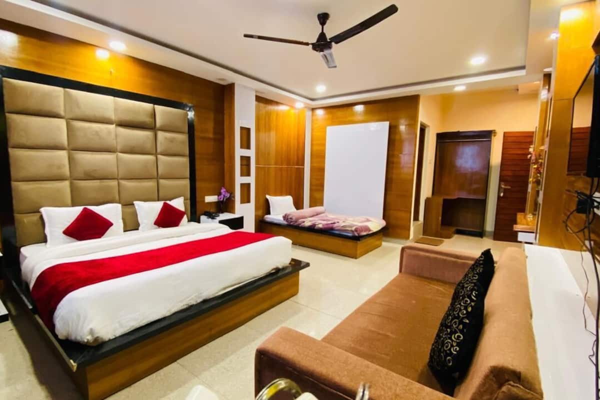 Quarto de hotel moderno com uma cama grande, um sofá, uma TV e um ventilador de teto.