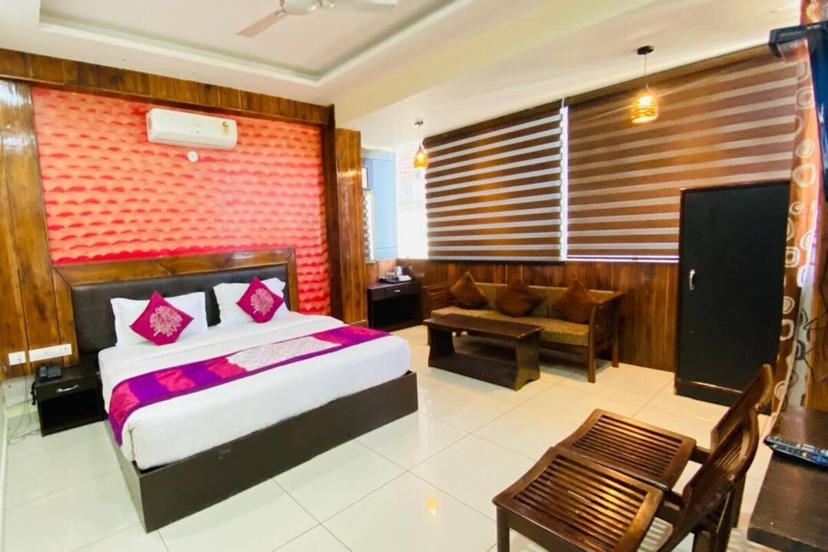 Quarto de hotel com cama, sofá, televisão e escrivaninha.