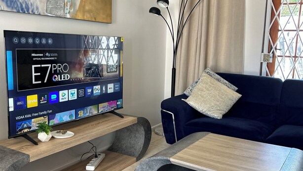 Ett modernt vardagsrum med en platt-TV, en blå soffa, ett soffbord och en dekorativ tavla på väggen.