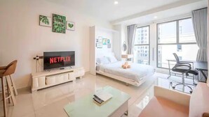 A modern hotel room with a bed, a TV displaying 'NETFLIX', a desk with a chair, and a large window. - Saigon Royal View Residence & River (Ho Chi Minh City)