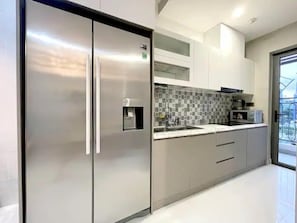 A modern kitchen with stainless steel appliances, a tiled backsplash, and white cabinetry. - Saigon Royal View Residence & River (Ho Chi Minh City)