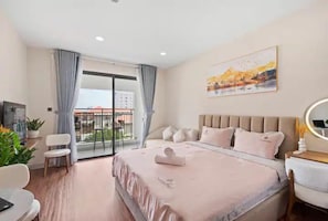 A hotel room with a bed, a desk, a chair, a TV, and a balcony with curtains. - Saigon Royal View Residence & River (Ho Chi Minh City)