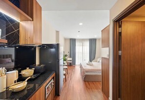 A modern kitchen with a black stove, wooden cabinets, and a dining area with a table and chairs. - Saigon Royal View Residence & River (Ho Chi Minh City)
