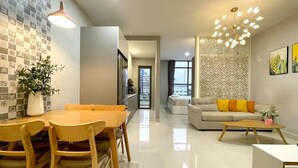A modern living room with a dining area, a sofa set, and a decorative wall. - Saigon Royal View Residence & River (Ho Chi Minh City)