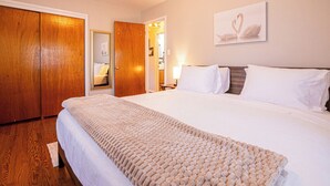 Ein Hotelzimmer mit einem großen Bett, einem hölzernen Kleiderschrank und einem gerahmten Bild an der Wand.