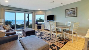 Un vaste espace de vie comprenant un balcon, une table à manger et un téléviseur.