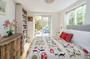 Quarto com uma cama, um armário de madeira, uma estante e vista para o exterior.