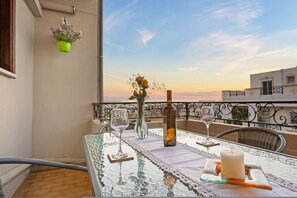 A balcony with a glass table set for two, featuring a candle, a bottle, and two wine glasses. - Artistic Apartment in Chania (Chania)
