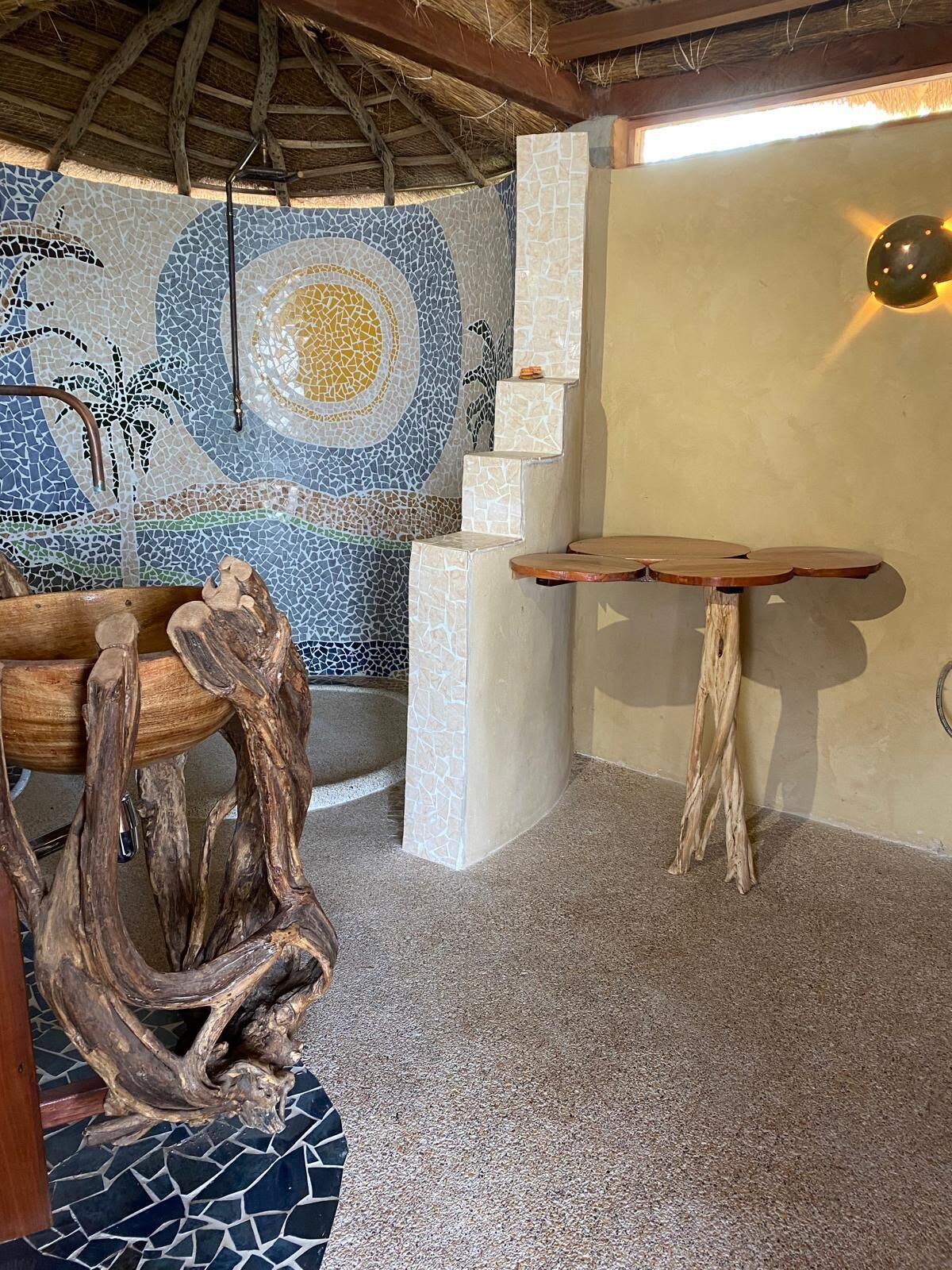 Um quarto com parede em mosaico, uma mesa de madeira e uma escultura de madeira única.