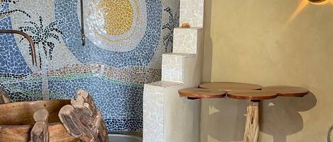 Um quarto com parede em mosaico, uma mesa de madeira e uma escultura de madeira única.