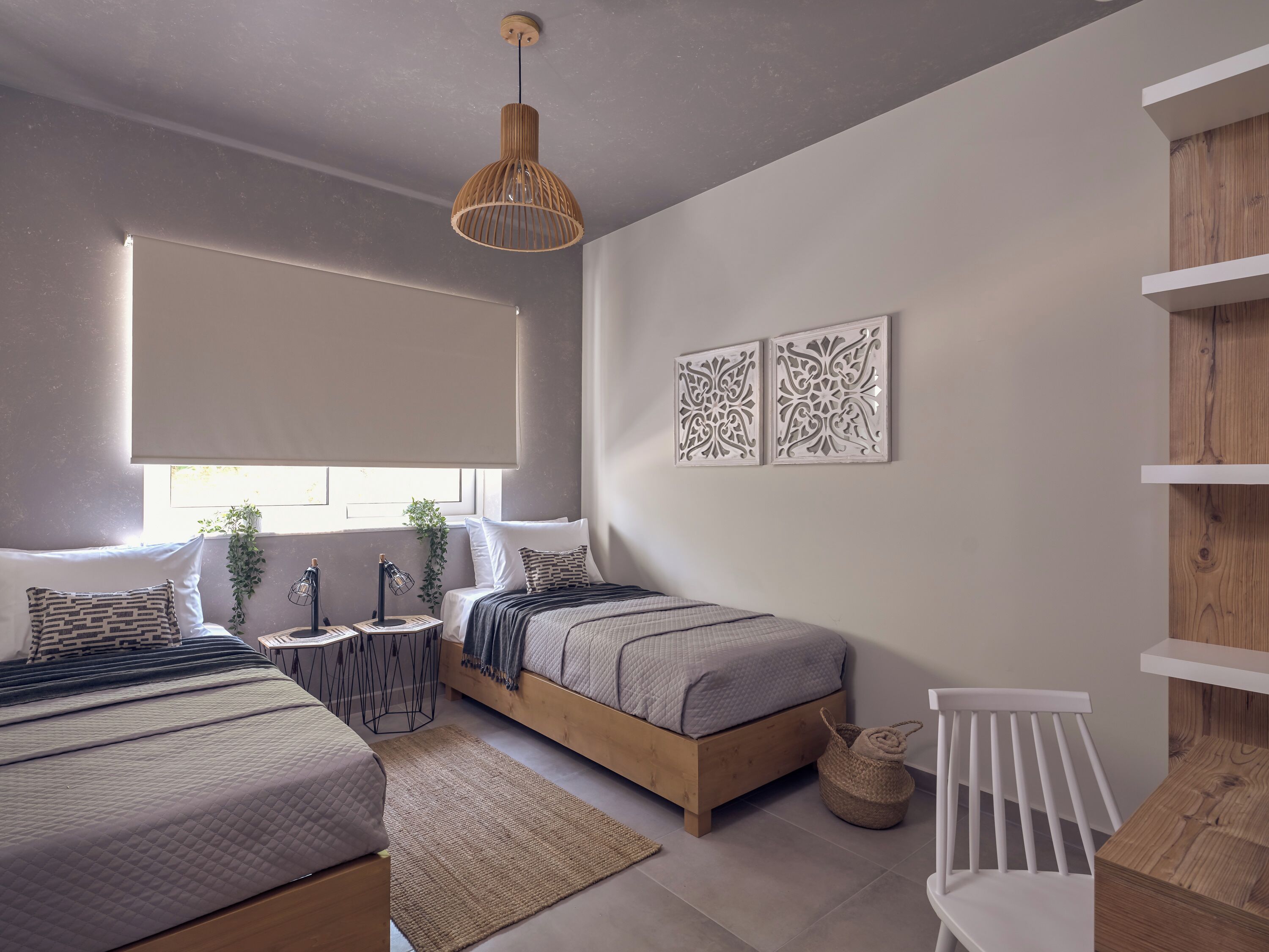 Un dormitorio moderno con dos camas, una mesita de noche, una lámpara, decoración en la pared y una ventana con persianas.