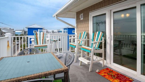 A balcony with a table and chairs, a sliding glass door, and a view of other buildings.