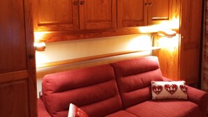 Een gezellig interieur van een camper met houten kastjes en een rode bank.