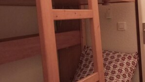 Een stapelbed met een houten frame en een sierkussen met bloemenprint.