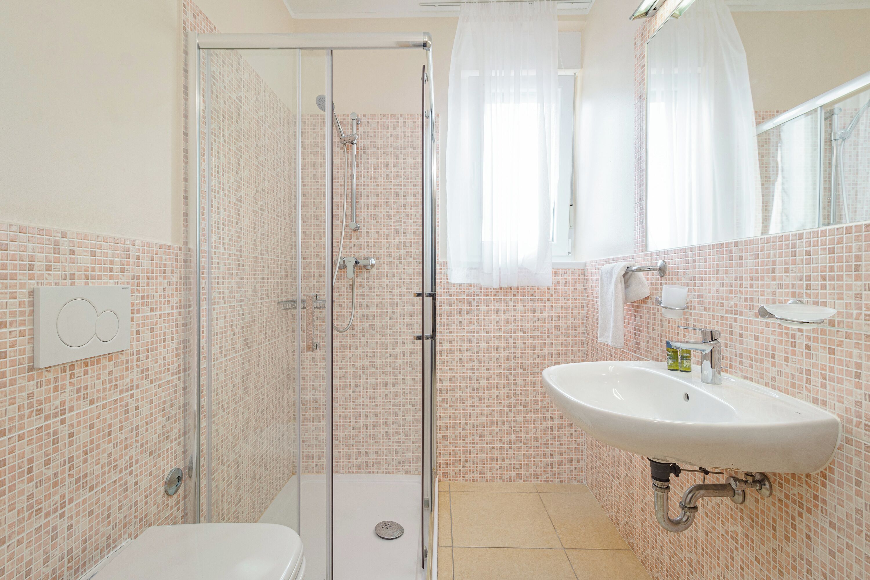 A bathroom with a glass-enclosed shower, a white sink, and a tiled backsplash.