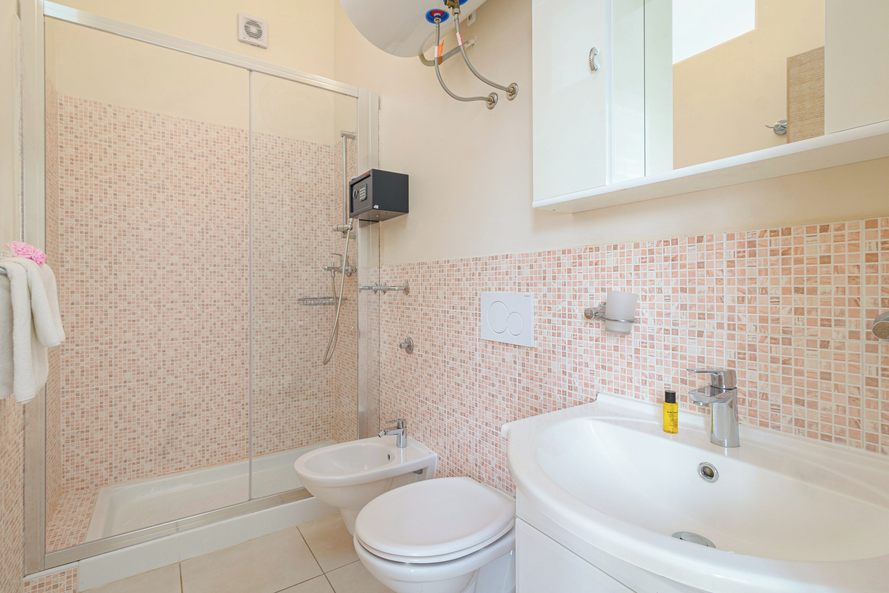A bathroom with a shower, bidet, toilet, and sink.