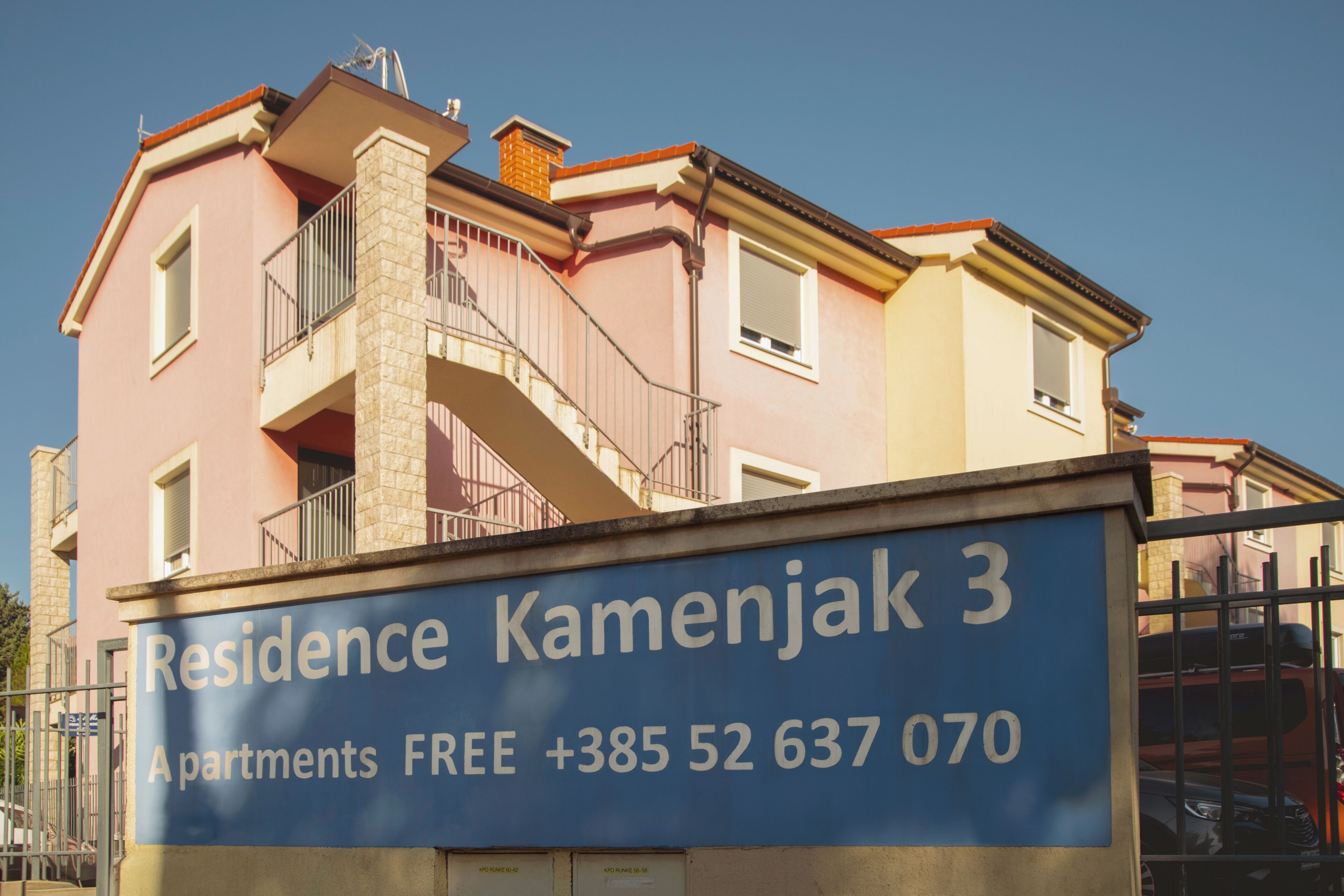 A building with a sign for 'Residence Kamenjak 3' and a contact number.