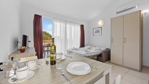 Una habitación de hotel con zona de comedor, cama y armario.
