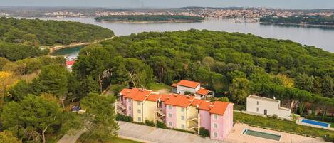 A residential area with a large body of water, green trees, and buildings with red roofs.