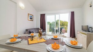 Comedor con mesa para cuatro, sofá y vista al exterior.
