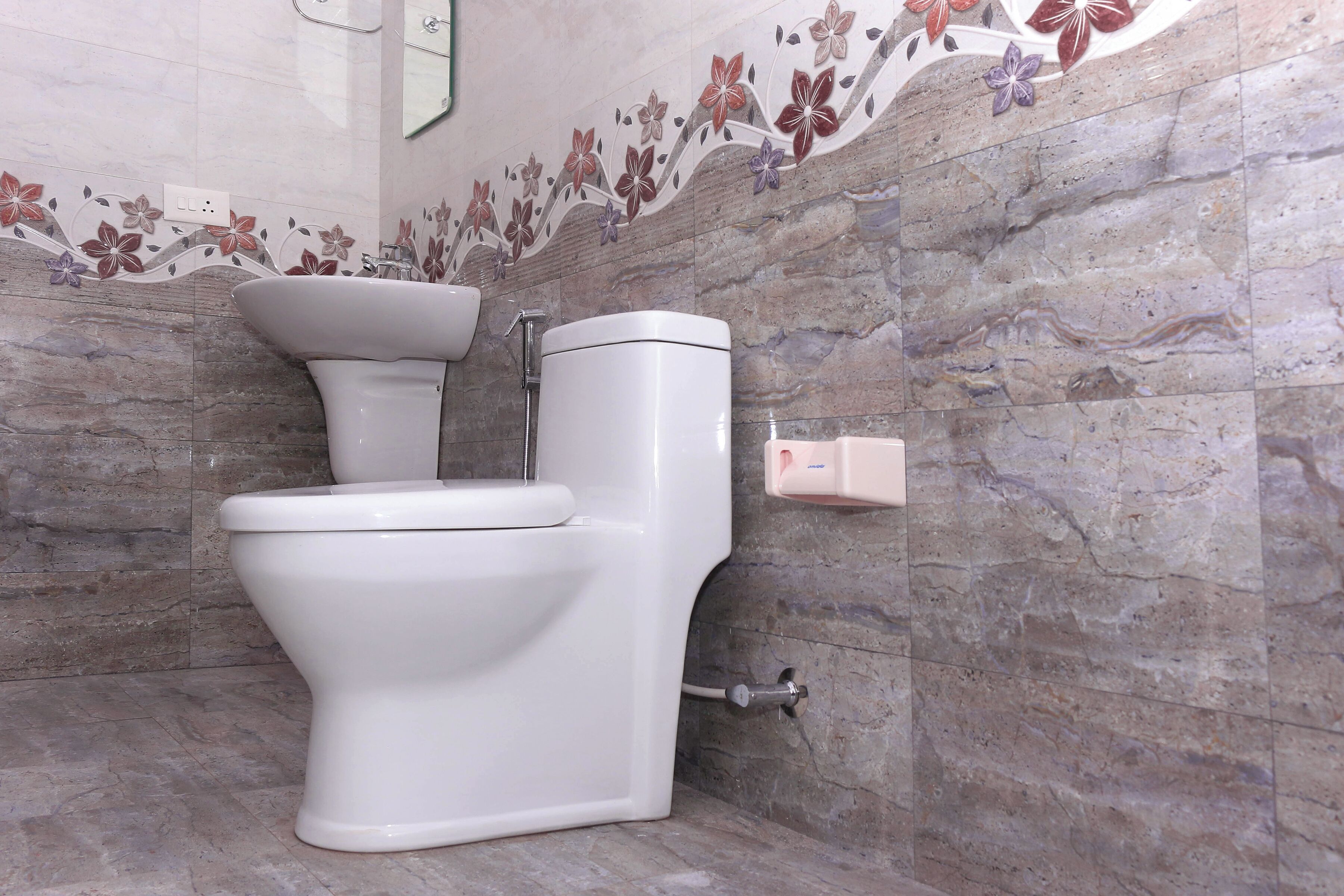 Une salle de bain équipée de toilettes, d’un lavabo et d’un distributeur de savon fixé au mur.
