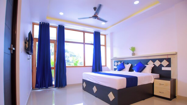 A modern bedroom with a large bed, a nightstand, a ceiling fan, and a window with curtains.