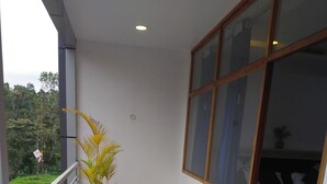 A balcony with a potted plant and a view of the greenery outside.