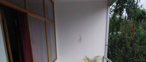 A balcony with a tiled floor, a potted plant, a railing, and a sign that reads "LUM".