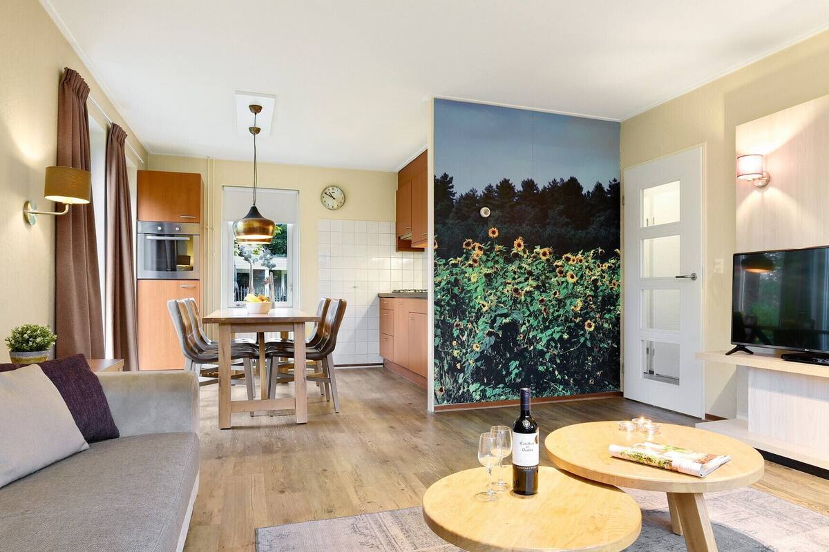 A modern apartment with a dining area, kitchen, living room, and a large TV.