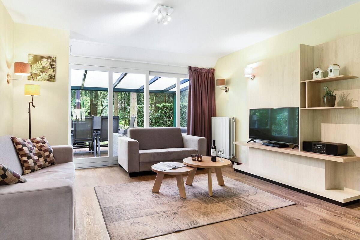 A modern living room with a sofa, armchair, TV, and shelves.