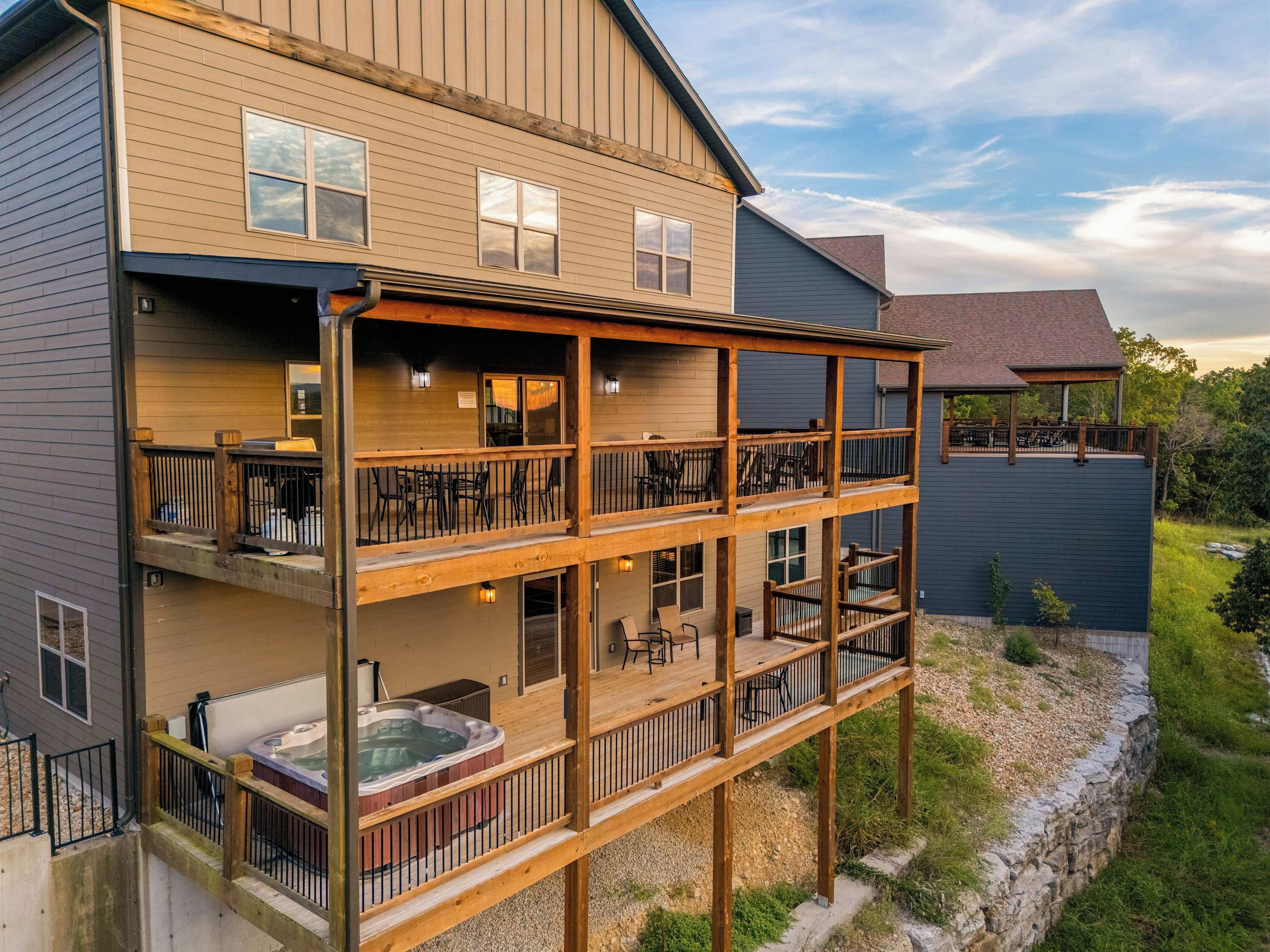 A multi-story building with a hot tub on the ground floor, outdoor seating on the upper levels, and a stone retaining wall.