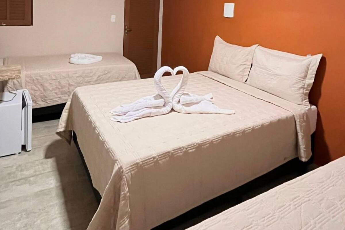 Ein Hotelzimmer mit zwei Betten, einem Nachttisch und einer Klimaanlage an der Wand.
