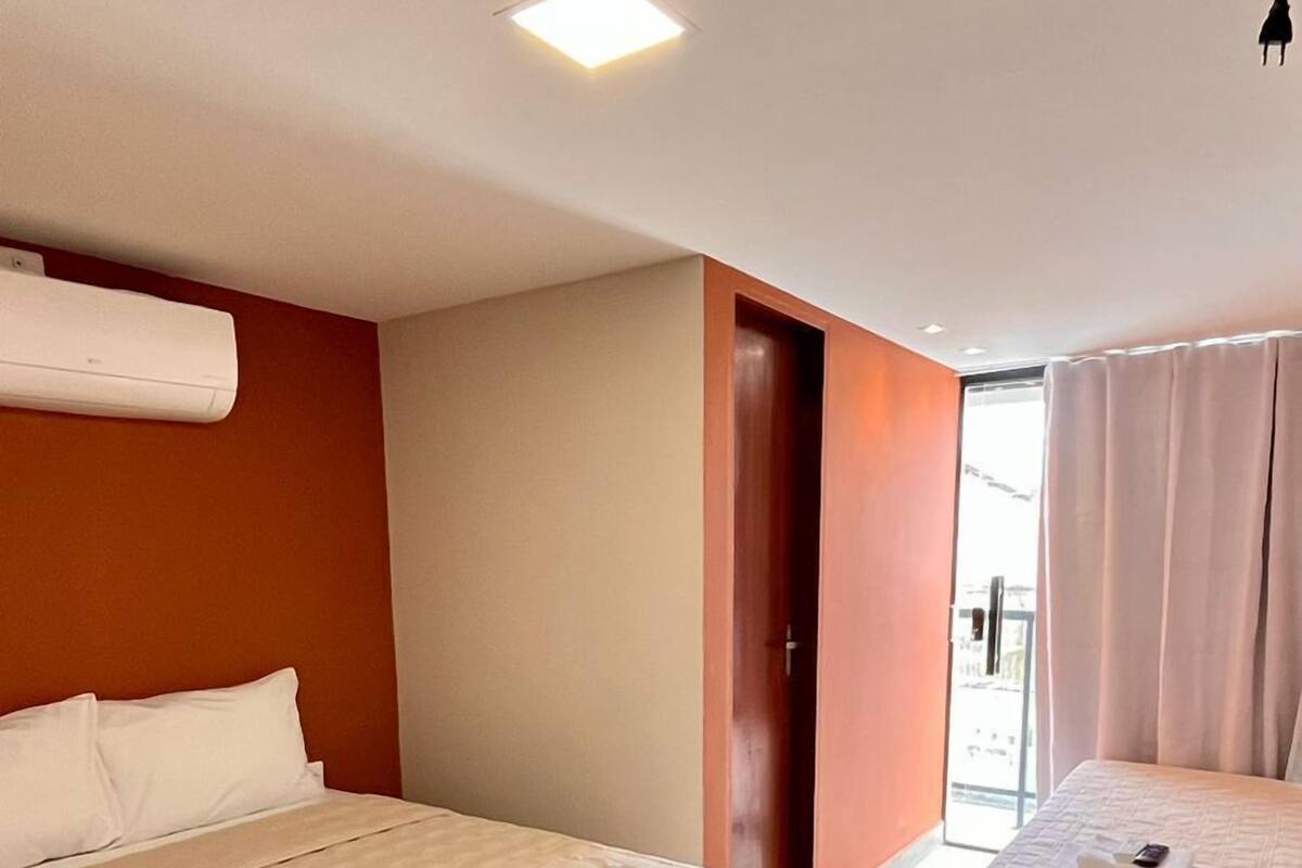 Ein Hotelzimmer mit zwei Betten, einer Holztür und Blick nach außen.