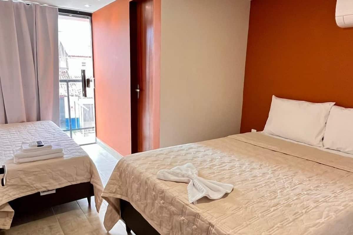 Ein Hotelzimmer mit zwei Betten, einem großen Fenster und Blick nach außen.