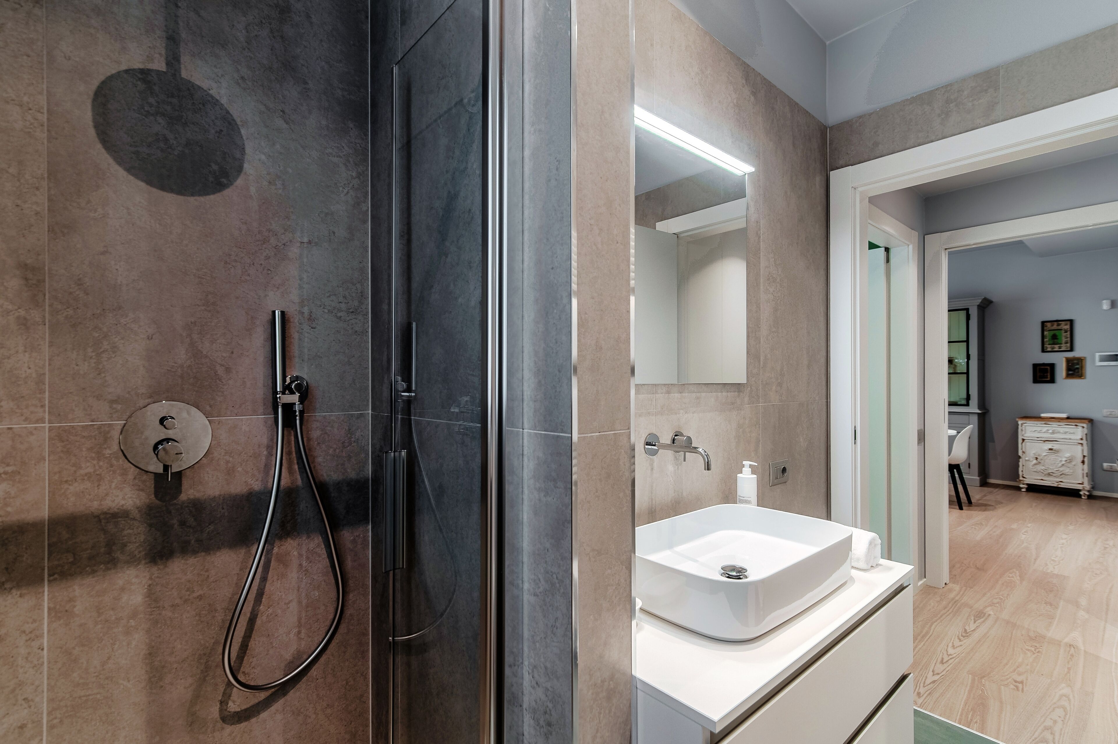 A modern bathroom with a glass-enclosed shower, a white sink, and a large mirror.