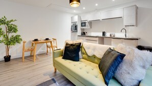 A modern living room with a sofa, a dining table, and a kitchen area. - No 3 @ The Rocket Rooms Apartments (Berwick-upon-Tweed)