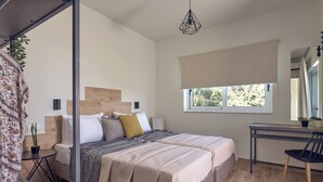 A bedroom with a bed, bedside table, chair, window, and a hanging light fixture.