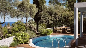 A wooden deck with a pool, lounge chairs, and a table with chairs.